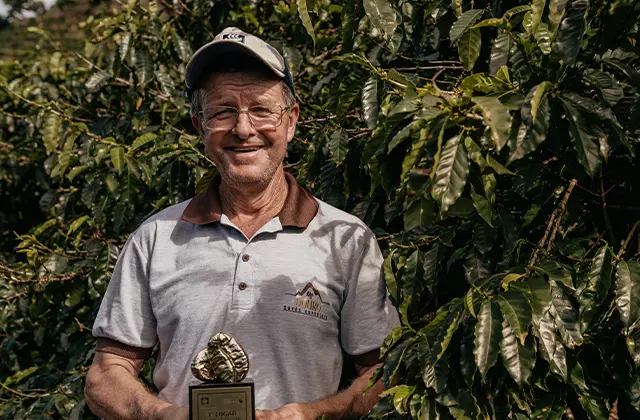 Homem segurando troféu e sorrindo